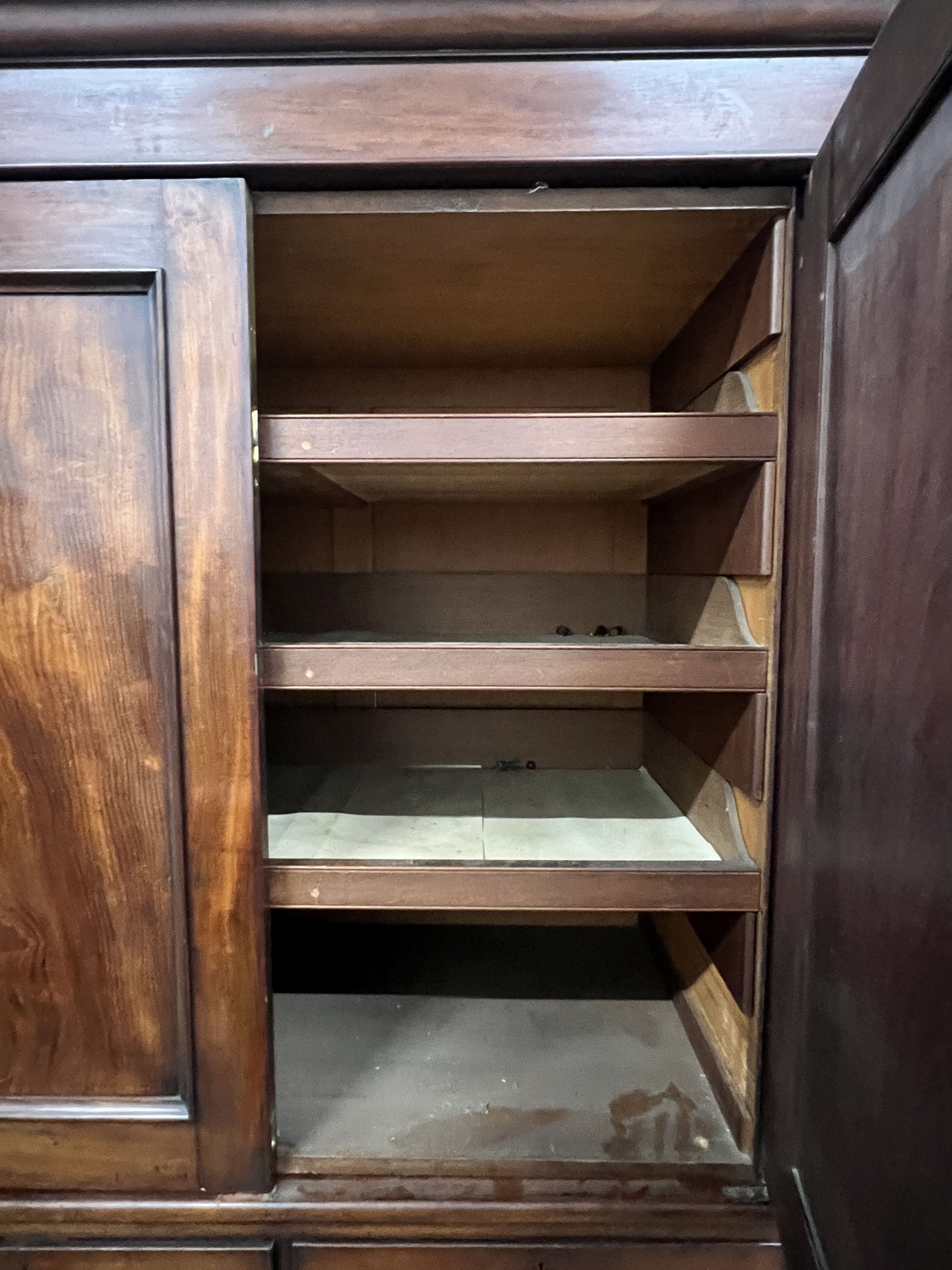 An early Victorian mahogany triple press cupboard, with three panelled doors over an arrangement of drawers and dummy drawers., width 178cm, depth 58cm, height 209cm